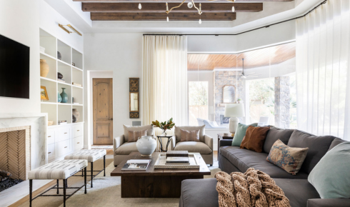 How can lowering the height of artwork or photos make a room feel more human and relaxed