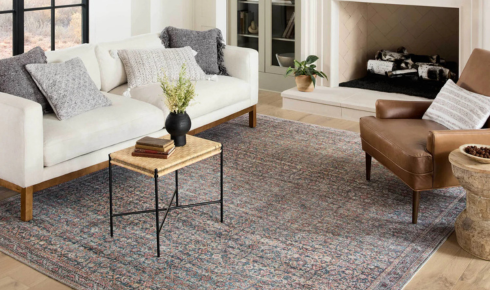 How can using a single large rug instead of many small ones make a room feel calmer
